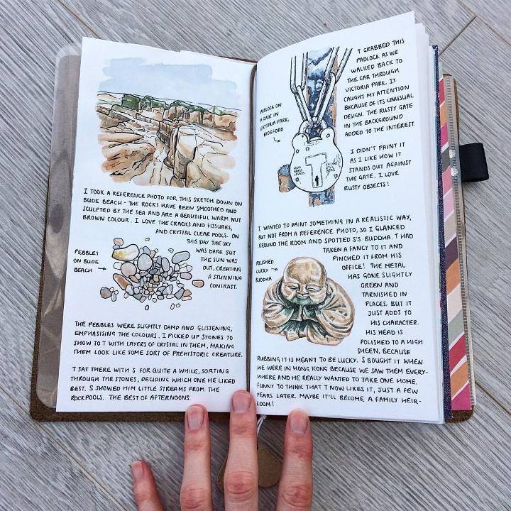 Midori travelers notebook with watercolour illustrations of some pebbles, a lock and a buddha ornament